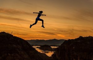 A woman jumps across a chasm