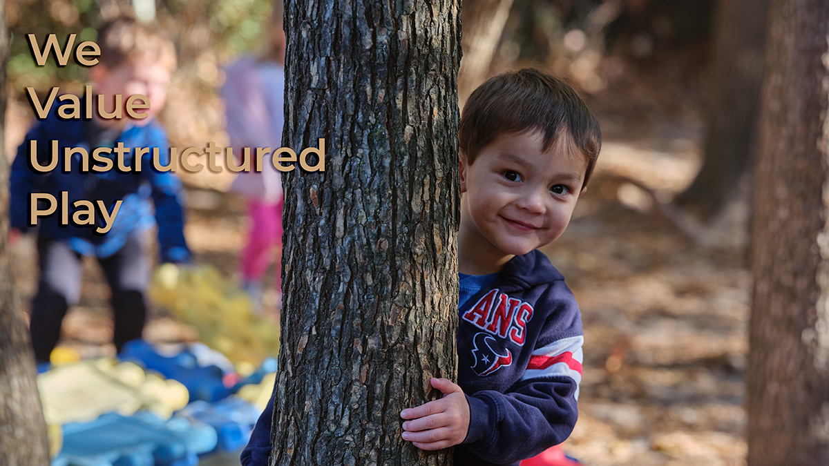A child peeks out from behind a tree